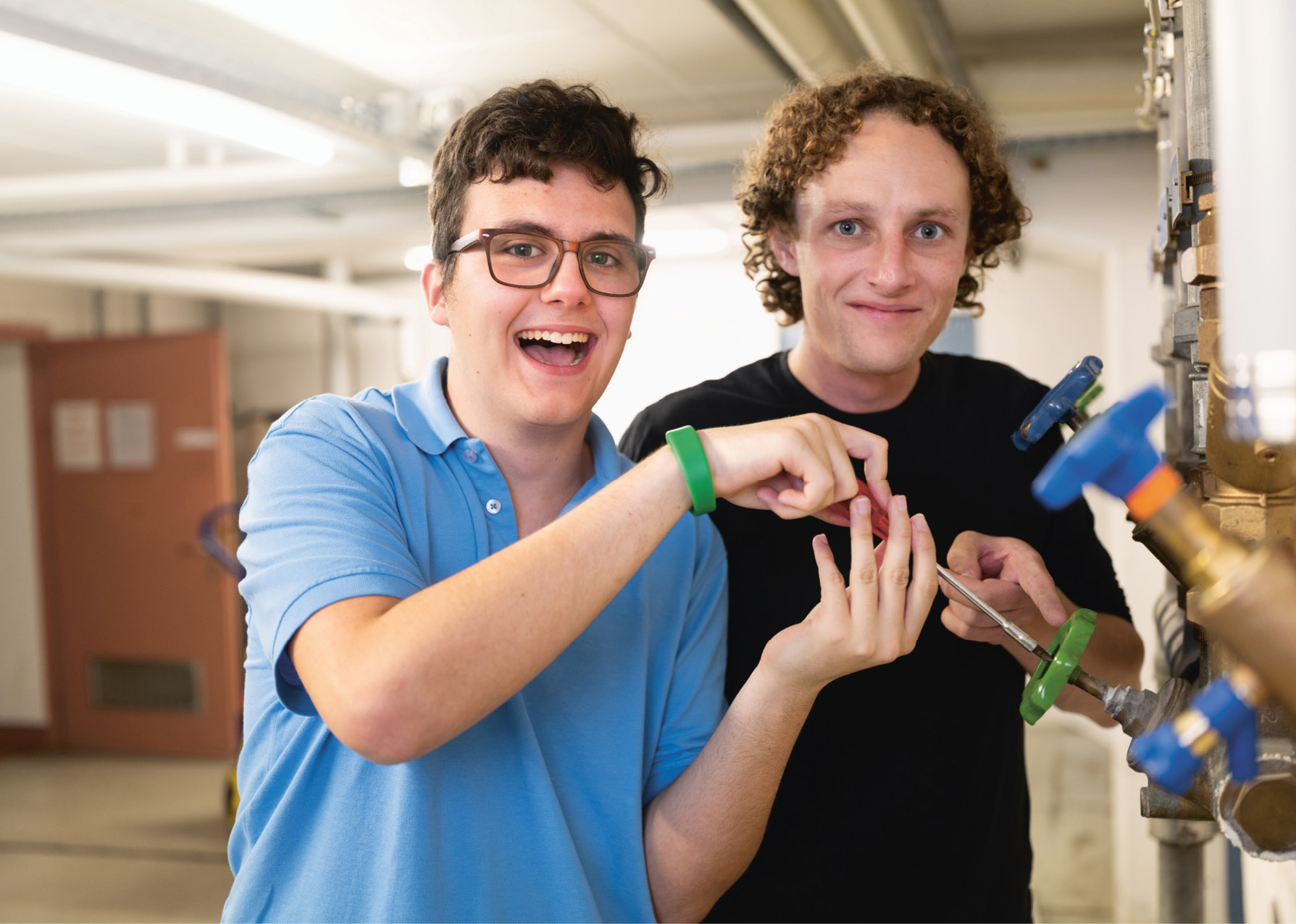 Berufsbildner und Lernender aus dem Team Technik und Unterhalt bei Unterhaltsarbeiten an einer Heizungsanlage.
