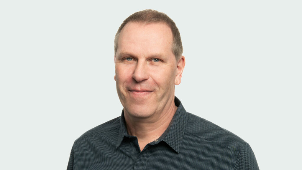 Ein Port&auml;tfoto von einem Mann. Er hat kurze Haare und tr&auml;gt ein schwarzes Hemd.