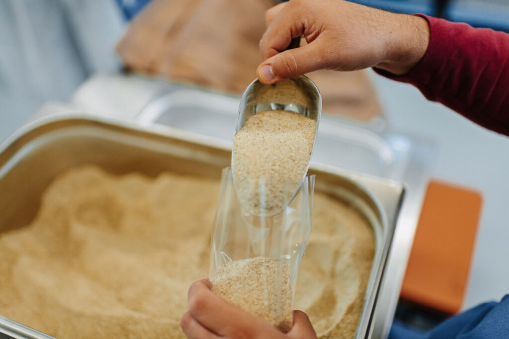 A spice is filled into a cellophane package by means of a small metal scoop.