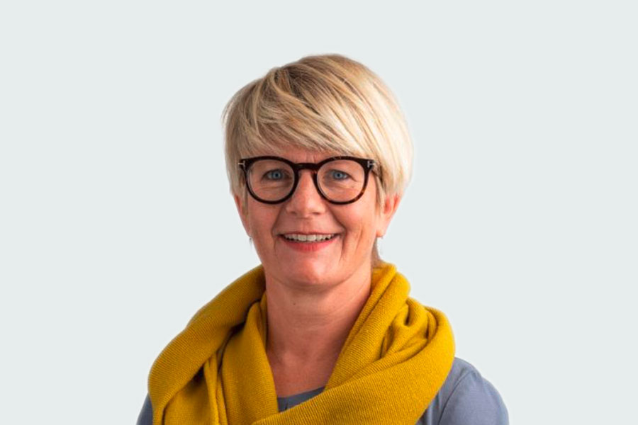 Frau mit blauer Bluse, gelbem Schal und Brille. Sie ist Leiterin des Fachbereichs Personal der Altra und Ansprechpartnerin für Fragestellungen rund um eine Anstellung bei der Altra.