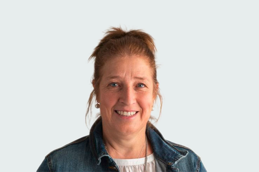 Sandra Arpagaus, contact person for training, supported education and partner companies. She is wearing a white shirt, denim jacket and earrings.