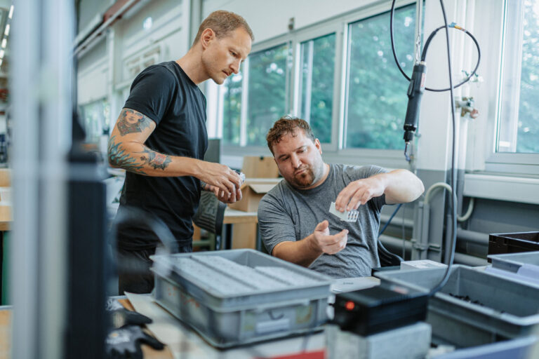 An employee explains his work in industrial assembly to another person.