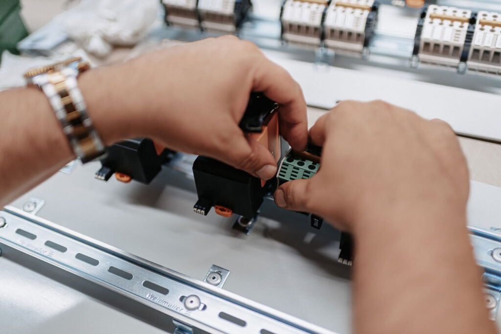 Two hands pre-assembling a control panel.