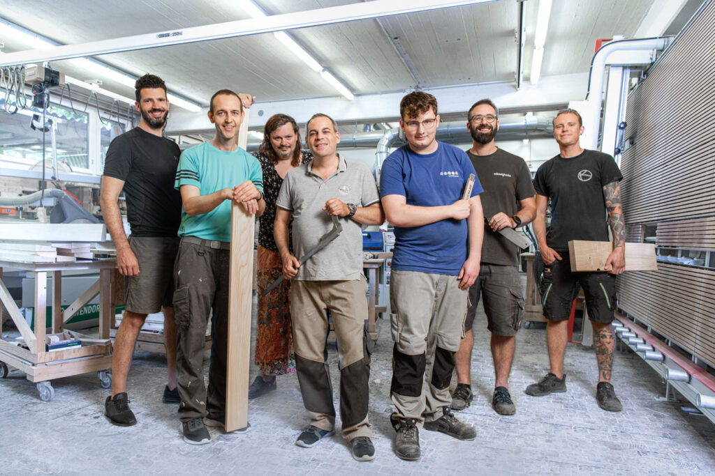 Seven people from the carpentry team. They are standing in a workroom.