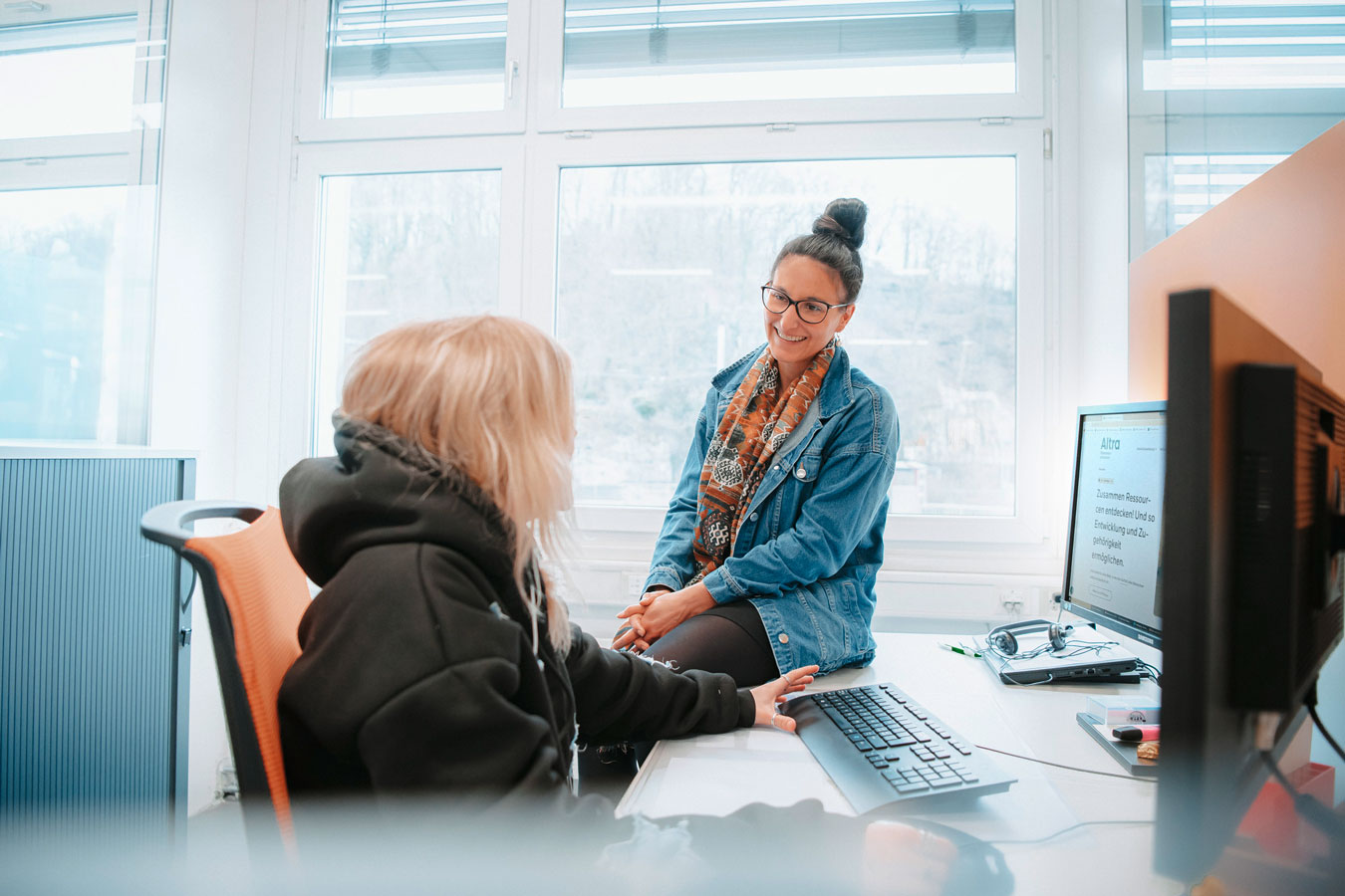 Zwei junge Frauen unterhalten sich vor dem Computer.