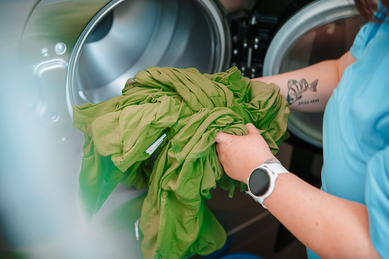 Grüne Wäsche wird aus der Waschmaschine genommen.