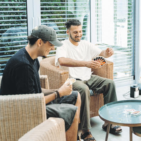 Zwei Männer sitzen an einem runden Tisch und spielen Uno