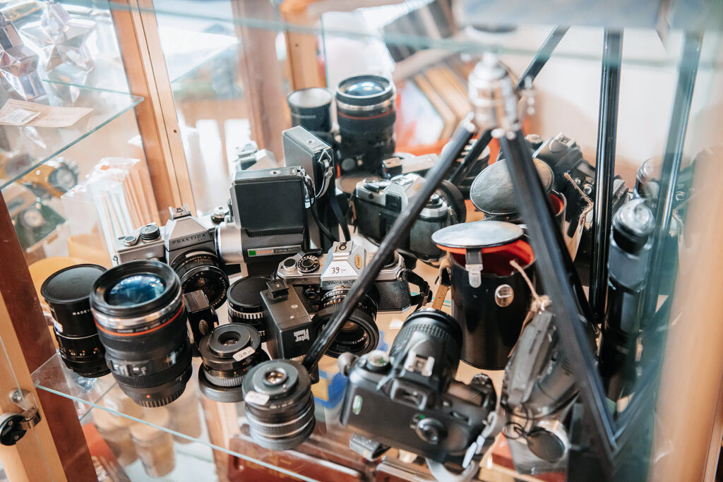 Many used cameras on a glass shelf
